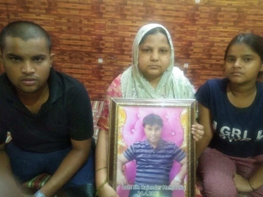 अपने बच्चों के साथ पति की तस्वीर लिए बबीता। दिल्ली की वाल्मीकि बस्ती की बबीता ने कोविड की दूसरी लहर में अपने पति को खो दिया।